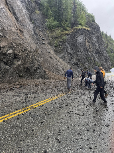 Drivers walk across a small slide area at Mile 68 on the Glenn Highway on Aug. 2, 2025
