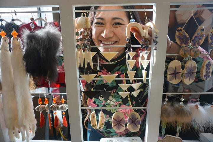 Britt'Nee Brower of Utqiagvik peers through hanging jewelry at her table at the Alaska Federation of Natives convention