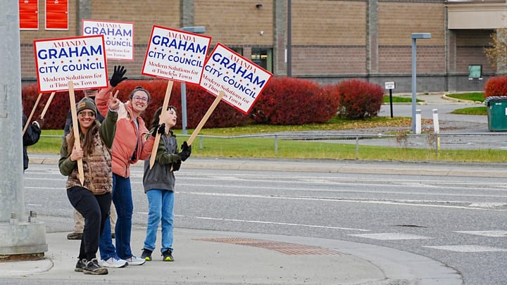 Palmer City Council Candidate Amanda Graham and several supporters wave signs