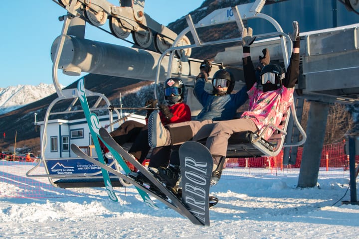 Skiers and a snowboarder ride the Skeetawk lift in Hatcher Pass durning the December, 2025 opening weekend