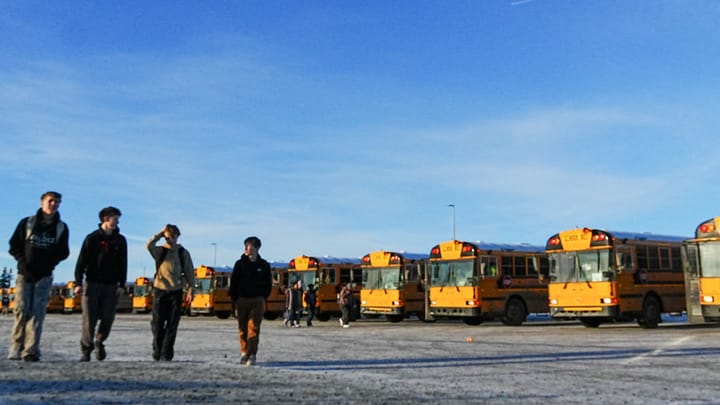 Students walk by school buses parked between Colony Middle and High Schools