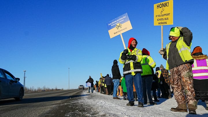 Bus workers wave signs on the strike line outside the Durham School Services bus barn on March 2, 2026.